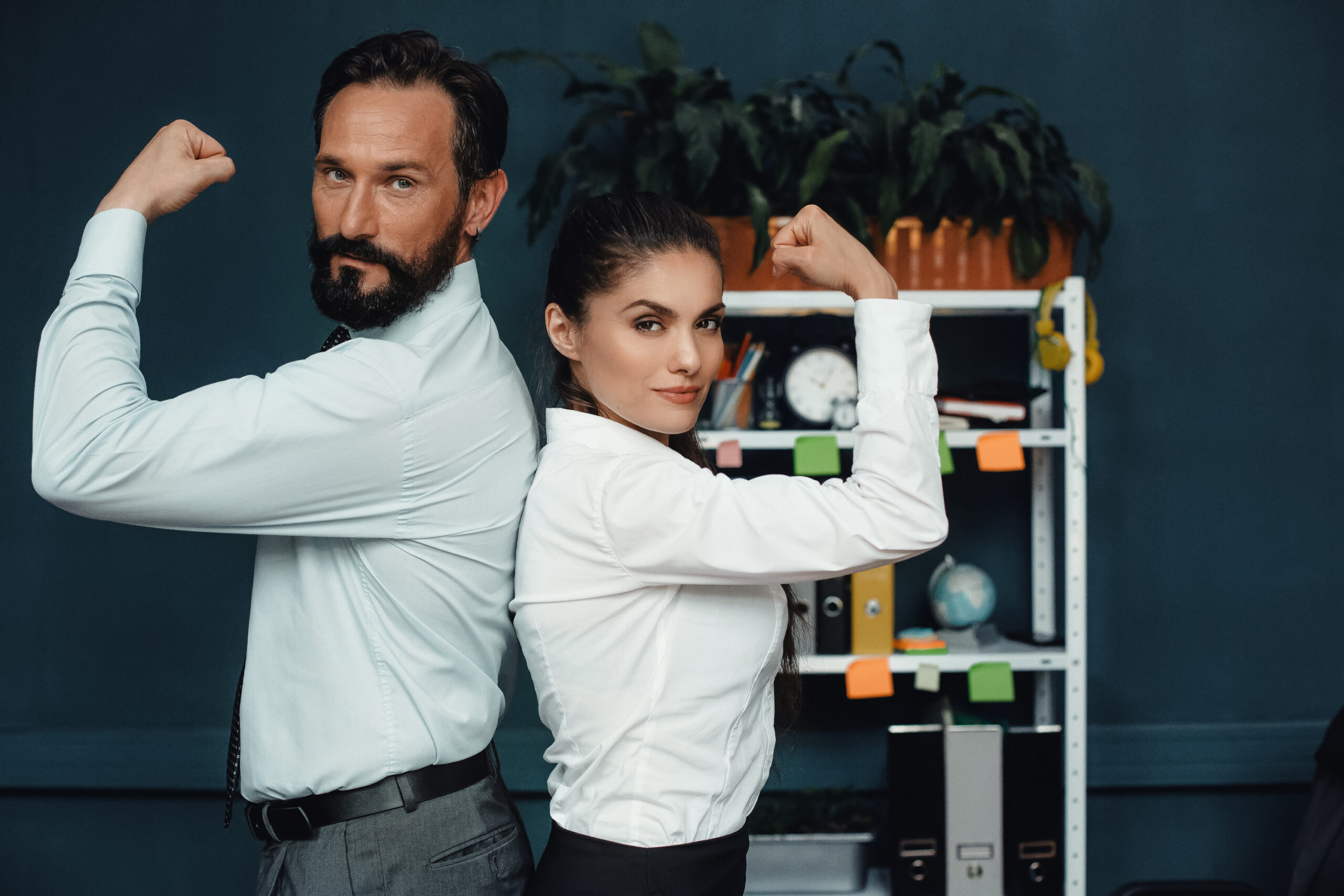 Two professionals strike a confident back-to-back pose in an office setting.