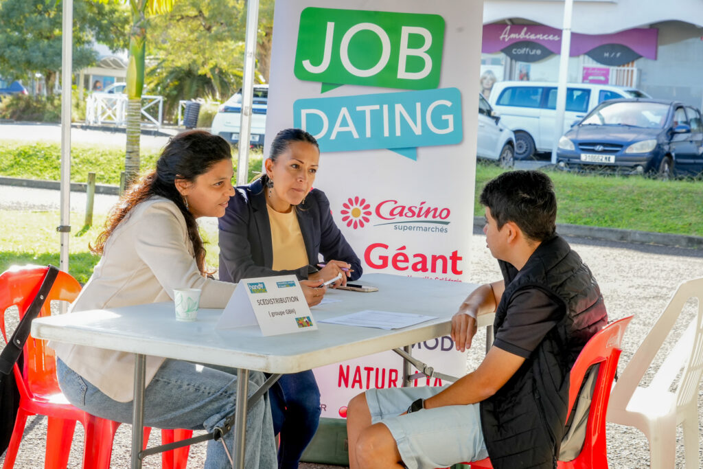 2 • province sud Three people sit at an outdoor job fair table two women and a man discussing documents under a job dating banner