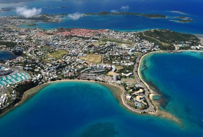 Aerial view of a coastal town with a large marina, turquoise bays, and sandy beaches surrounding a densely built shoreline.